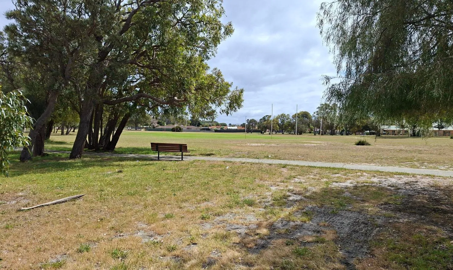 Grassed area with park bench and football goals in background